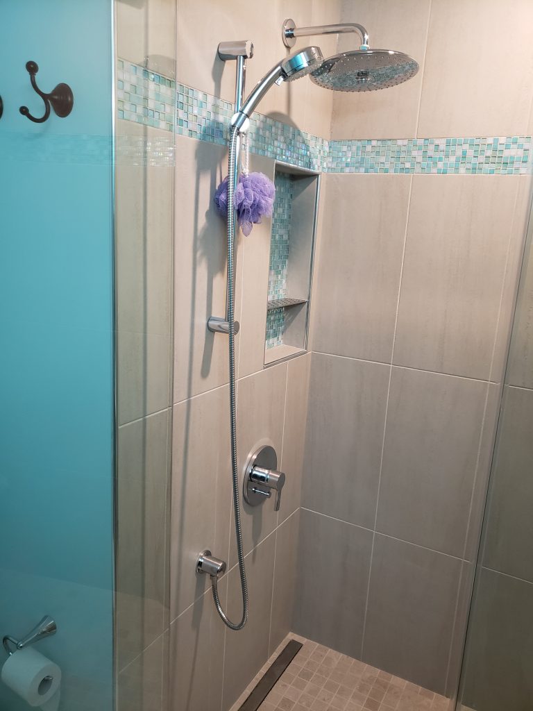 Custom condo bathroom walk-in shower with aquamarine tile and glass door.